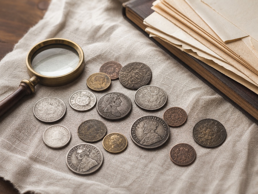 Old British coins with a magnifying glass on an appraisal table