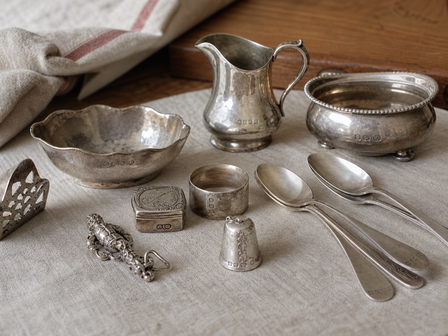 Antique silverware and decorative silver items on linen